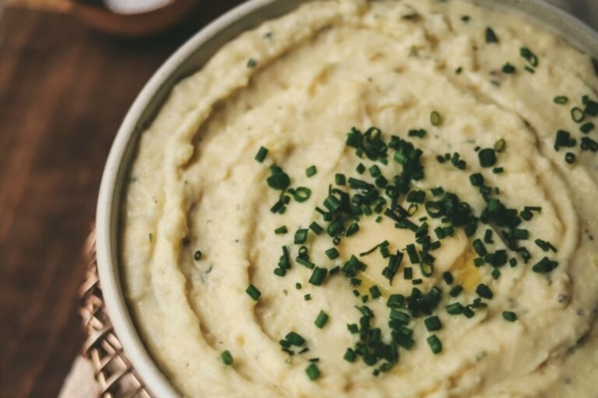 A bowl of mashed potatoes with chives on top.