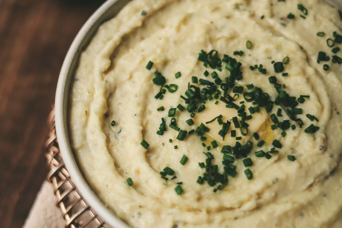 A bowl of mashed potatoes with chives on top, perfect as a side dish for turkey.