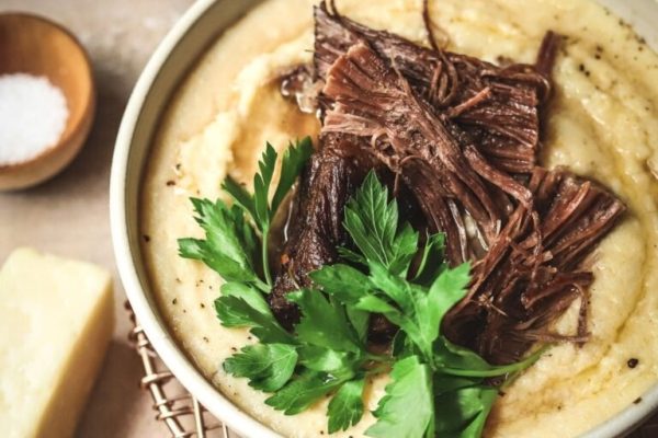 A bowl of soup with meat and parsley.
