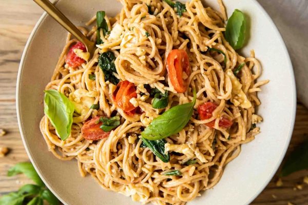 A bowl of pasta with tomatoes and basil in a brie sauce.