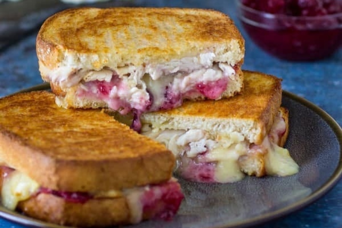 A grilled chicken sandwich with cranberry sauce on a plate, perfect for leftover turkey recipes.