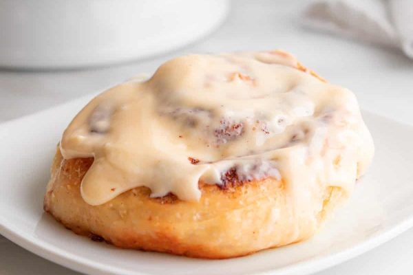 Cinnamon rolls with icing on a white plate.