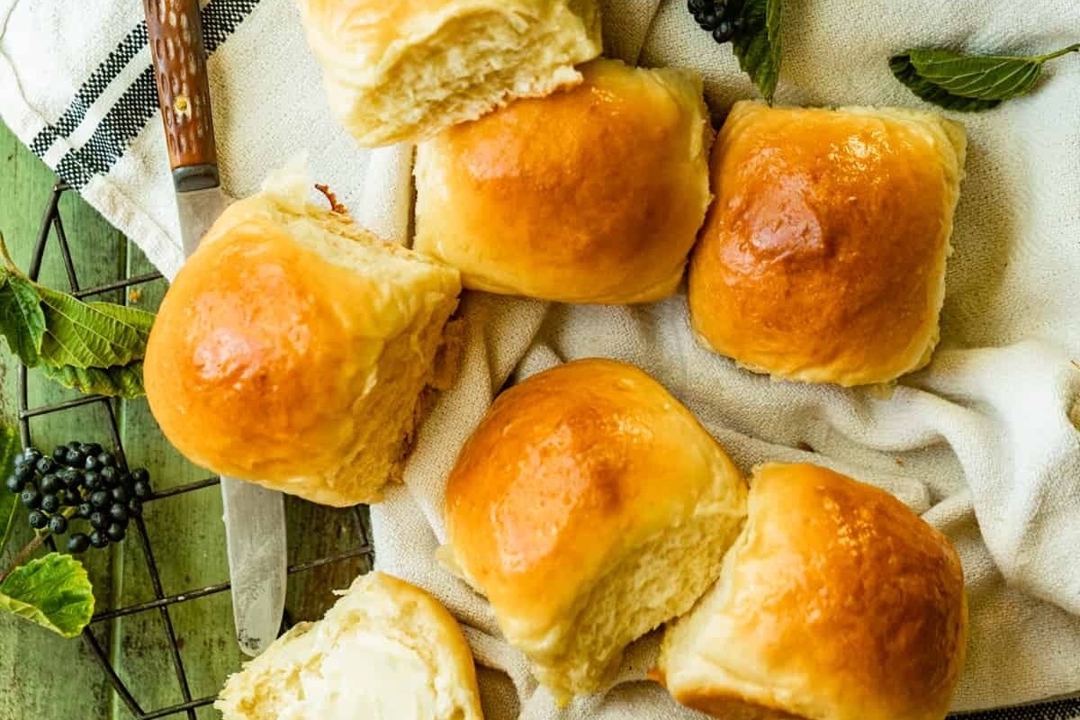 Delicious bread basket with butter and berries on a white cloth.