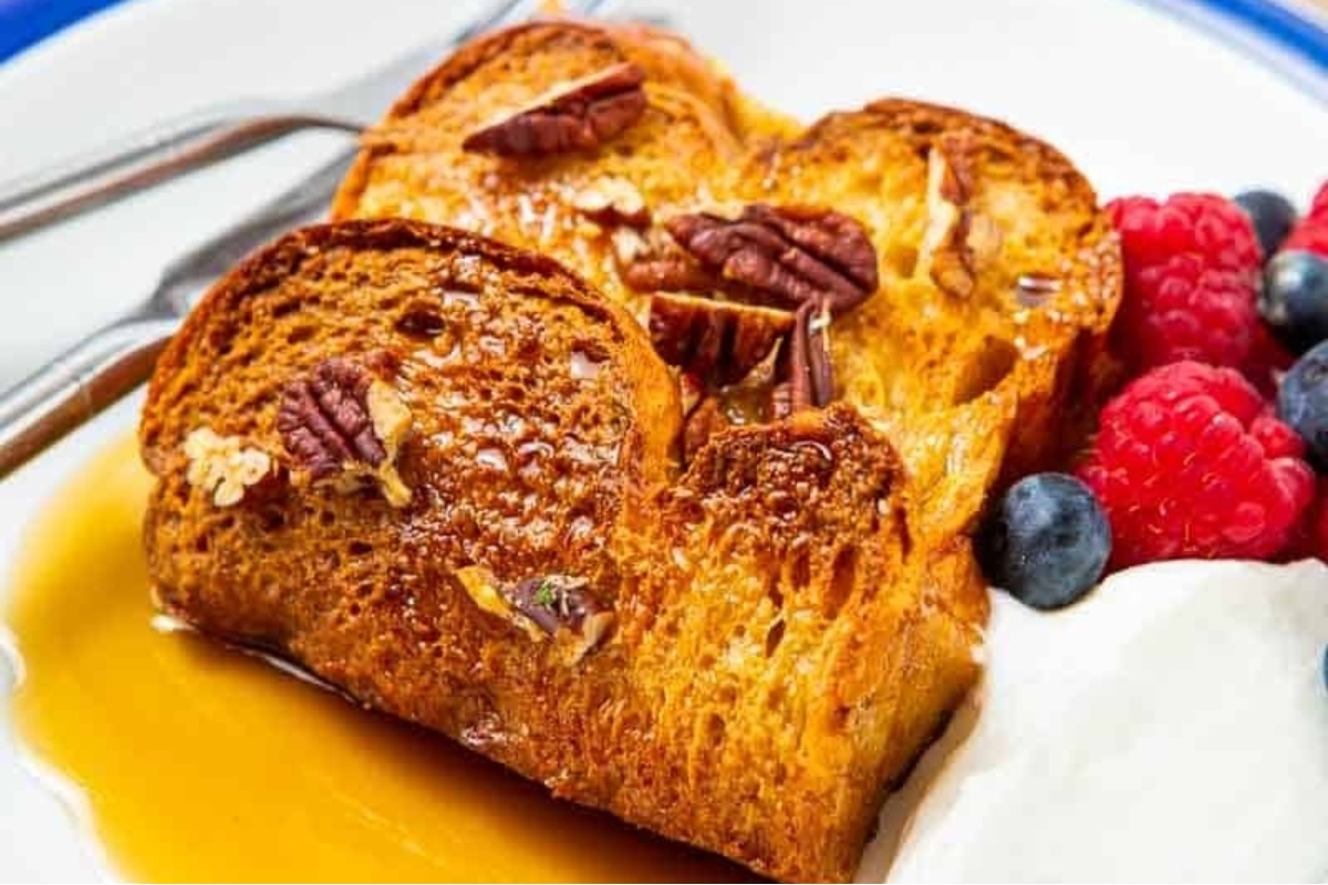 Christmas breakfast recipe for French toast with pecans and berries on a plate.
