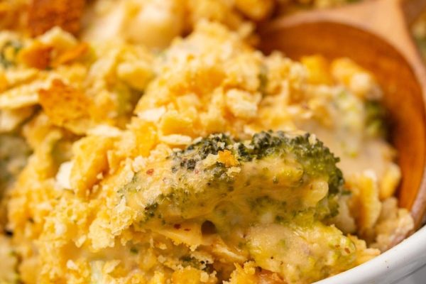A cheap potluck dish of broccoli and cheese casserole with a wooden spoon.