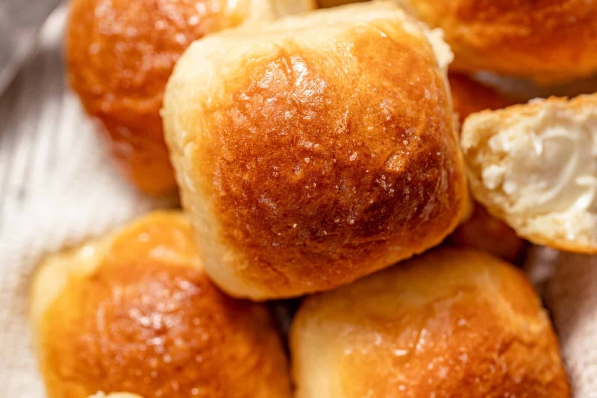 A bread basket filled with a pile of bread rolls.