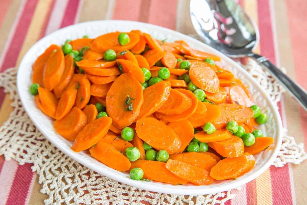 Frozen peas and carrots in a white bowl.