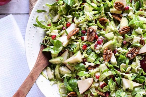 A bowl of brussels sprout salad with apples and pomegranate.