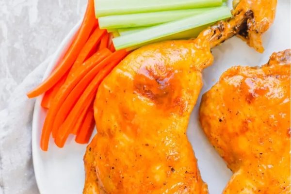 Buffalo chicken wings on a plate with carrots and celery.