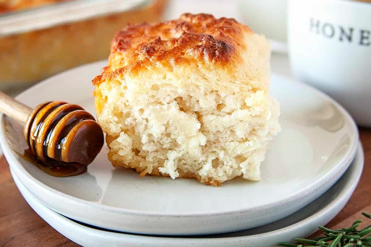A plate with a piece of honey biscuits next to a cup of coffee.