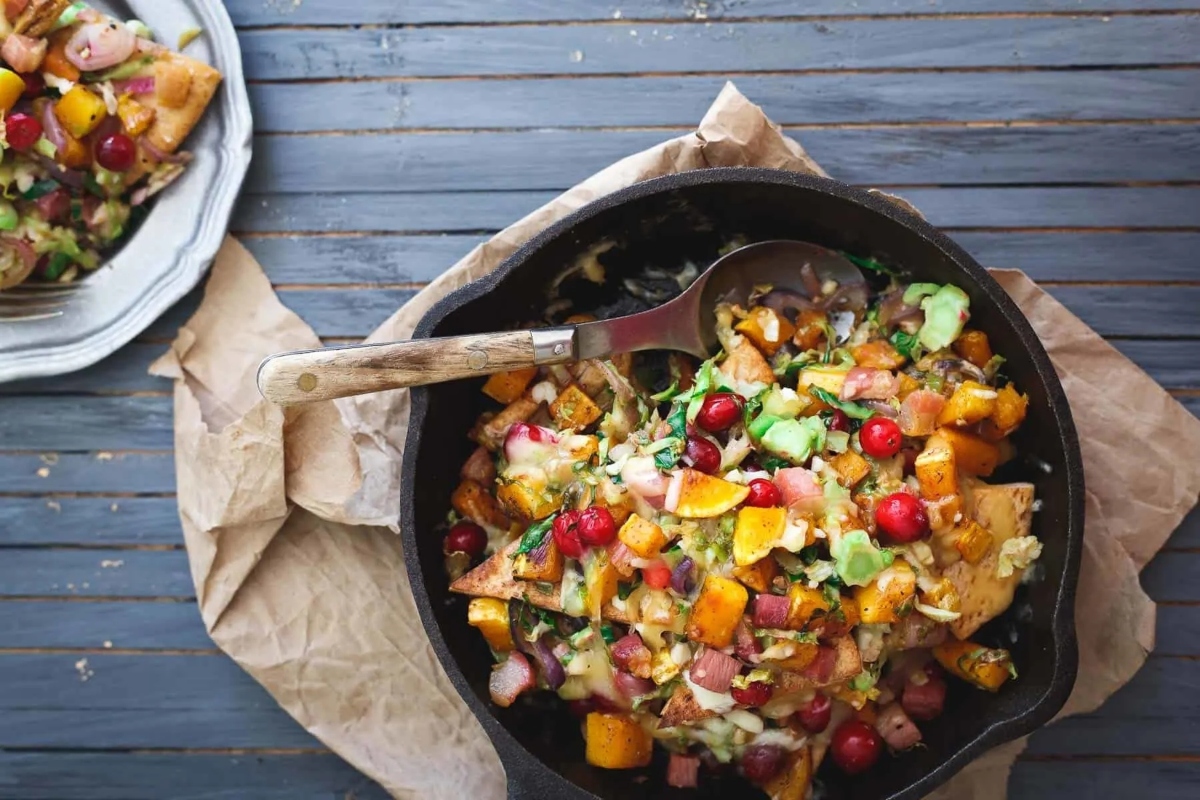 A skillet filled with vegetables and ham.