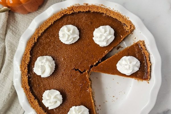 A slice of pumpkin pie on a plate with whipped cream.