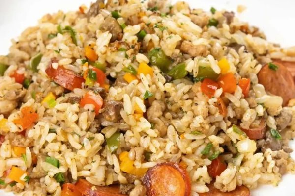 Fried rice with sausage and vegetables on a white plate.