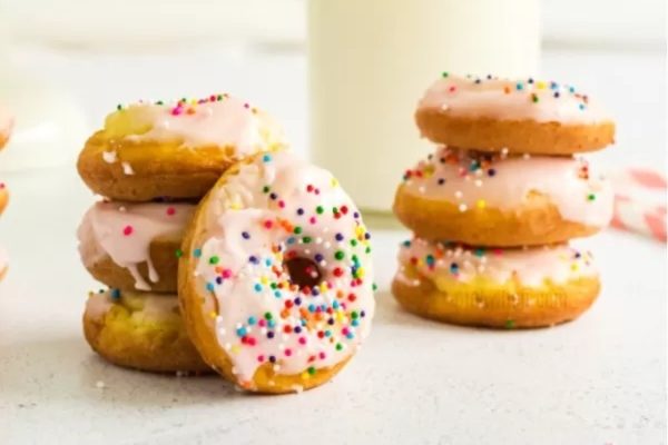 A stack of donuts with sprinkles and milk.