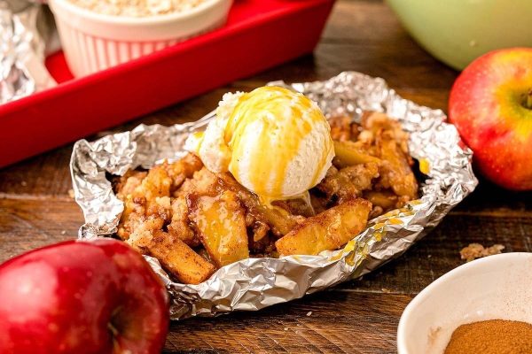 Apple crisp in foil with ice cream and apples.
