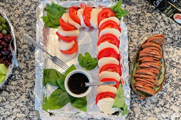 A festive tray of vegetables, olives, and Christmas-themed charcuterie boards displayed on a counter.