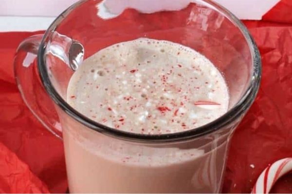 A decadent glass of peppermint hot cocoa with candy canes, perfect for a holiday treat.