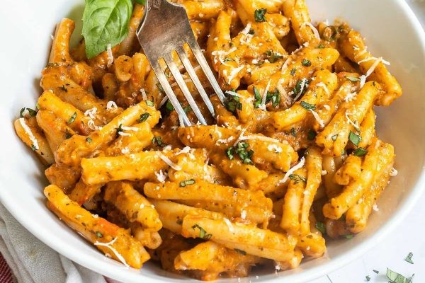 Penne pasta in a white bowl with a fork.