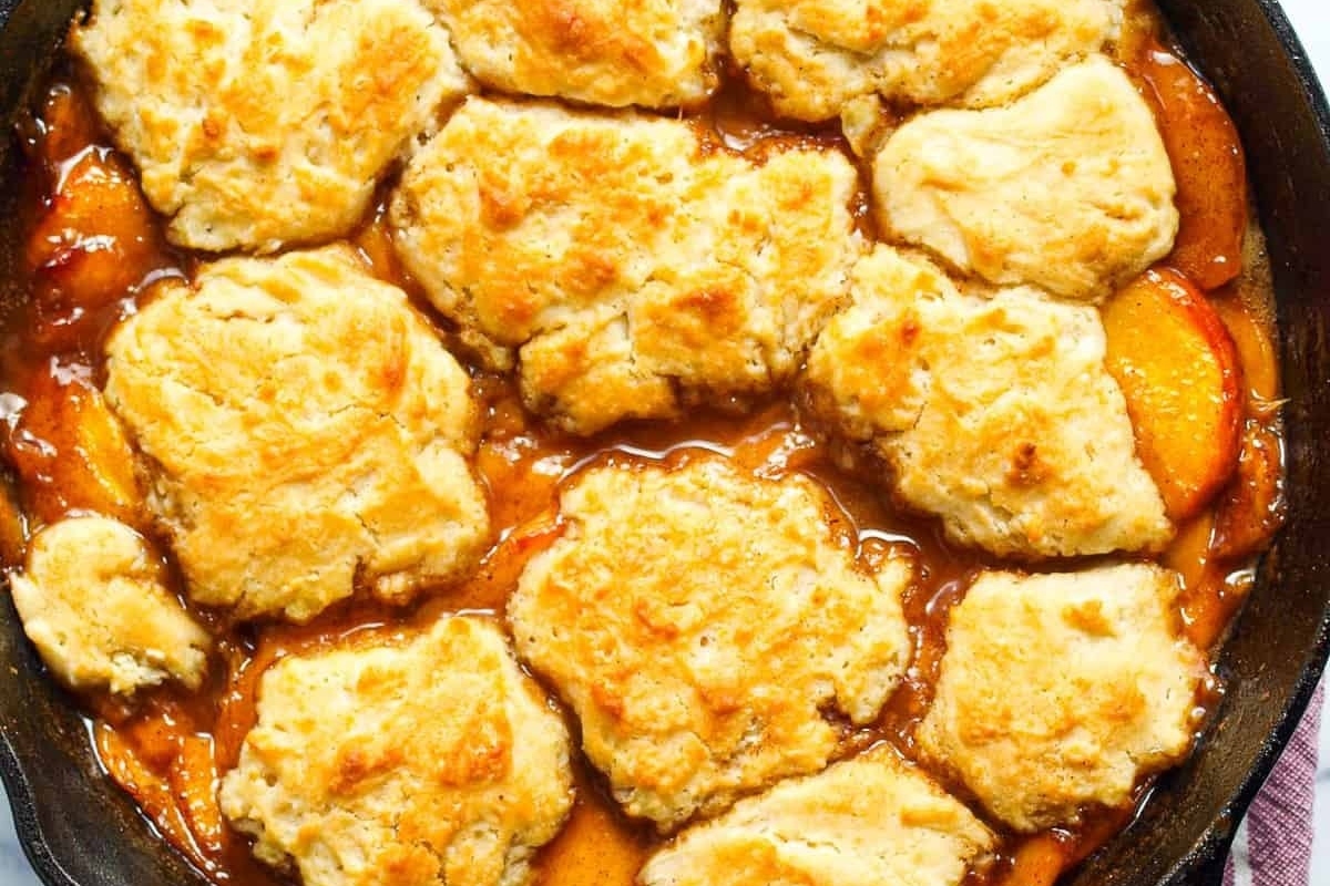 Country style peach cobbler baked in a cast iron skillet.