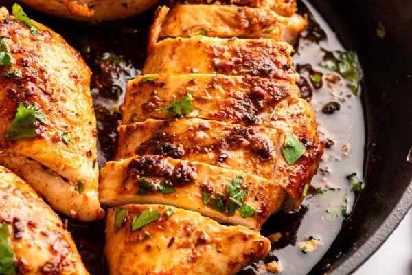 Chicken breasts in a skillet with herbs.