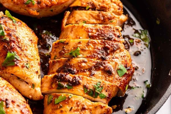 Chicken breasts in a skillet with herbs.