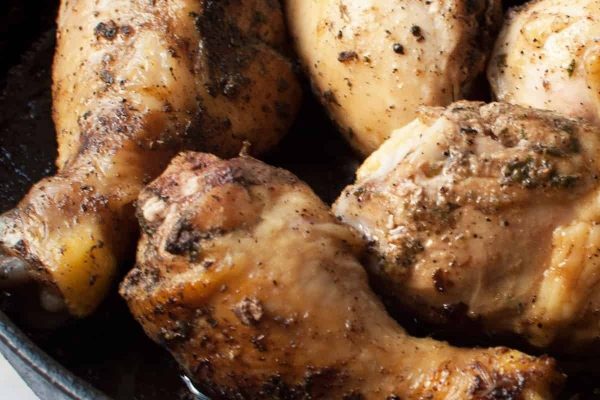 Chicken legs in a skillet with herbs.