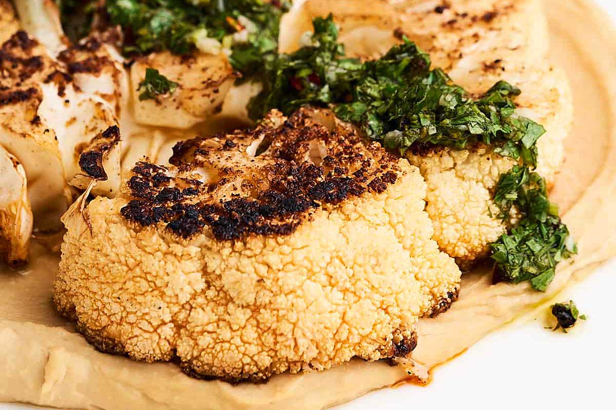 Roasted cauliflower on a plate with a sauce on top, perfect for a date night.