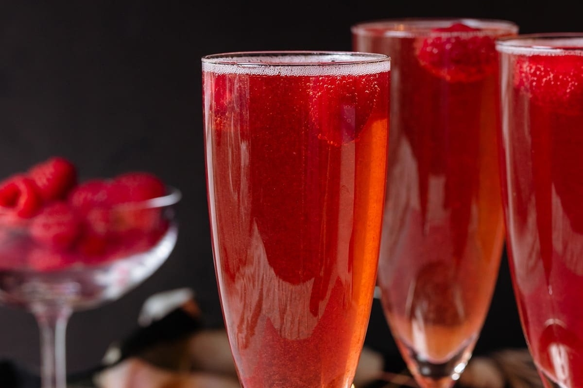 Three glasses of champagne with raspberries, creating elegant cocktails.