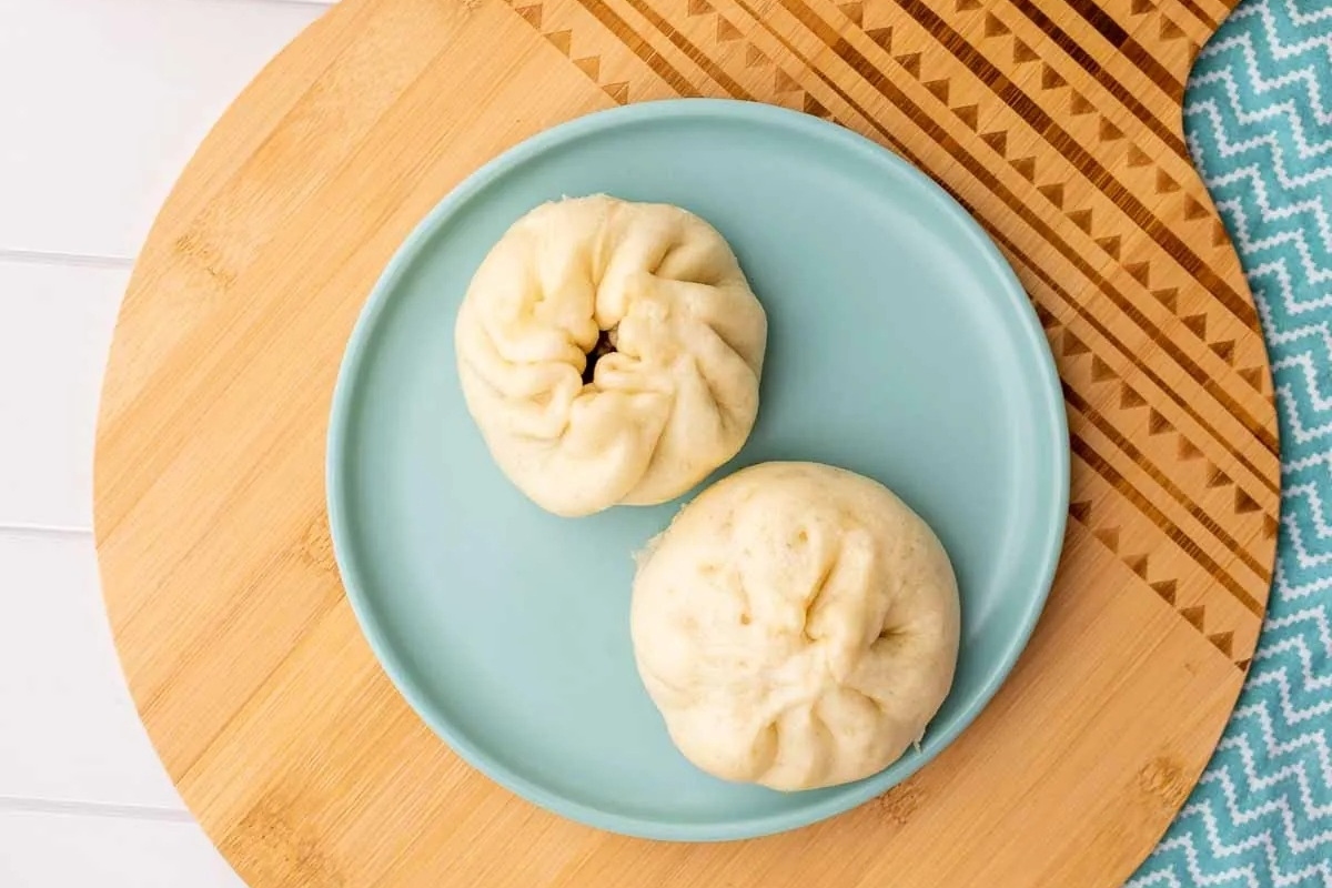 Two buns served on a wooden board.