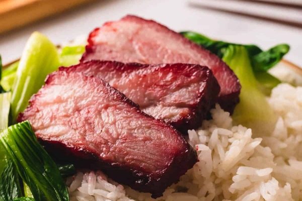 A budget-friendly plate of Asian pork with rice and greens, perfect for takeout meals.