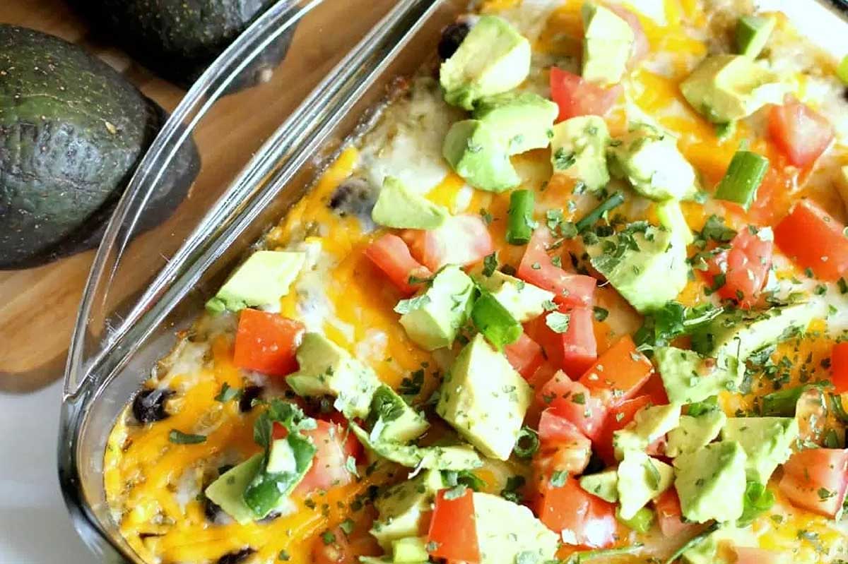 A casserole dish with avocado, tomatoes and cheese.