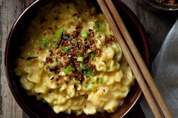 A bowl of ramen noodles and chopsticks on a wooden table.