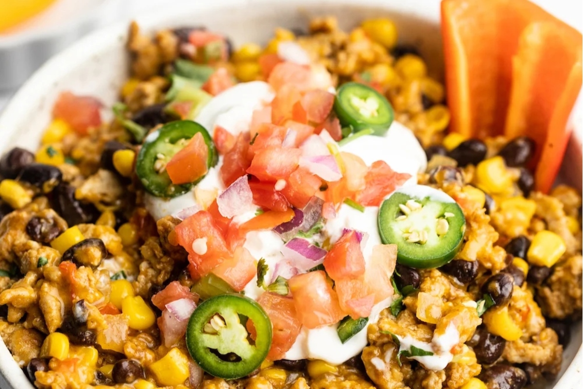 A bowl of Mexican rice with ground turkey, black beans, and sour cream.
