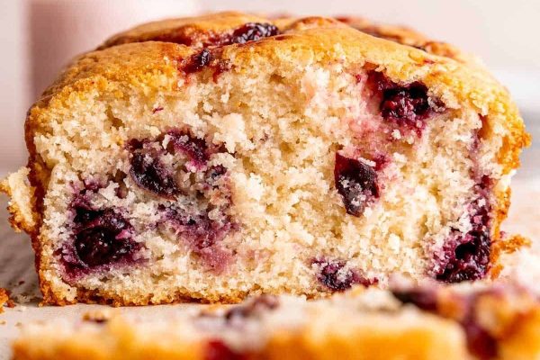 A slice of blueberry bread on a cutting board.