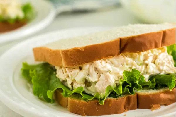 Chicken salad sandwich on a white plate.