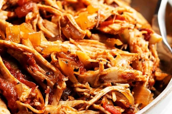 A close up of bone-in shredded chicken breast in a pan.