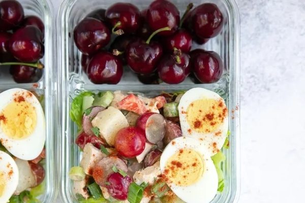 Two clear containers with a salad and a hard boiled egg.