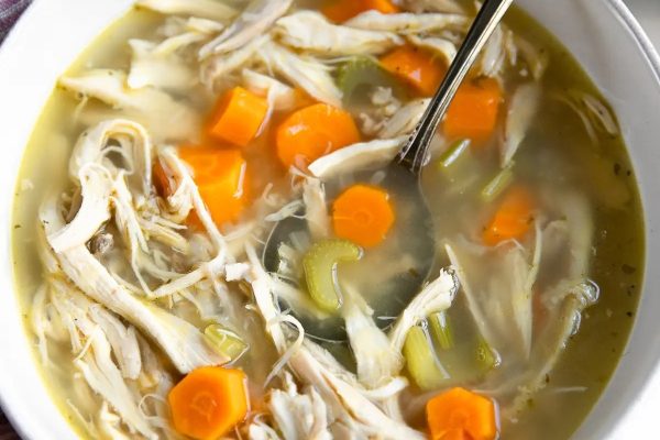 A bowl of chicken noodle soup with carrots and carrots.