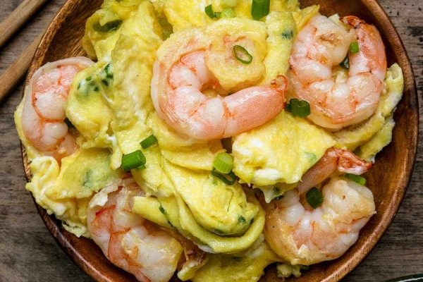 Asian-inspired shrimp and egg dish served in a wooden bowl with chopsticks.