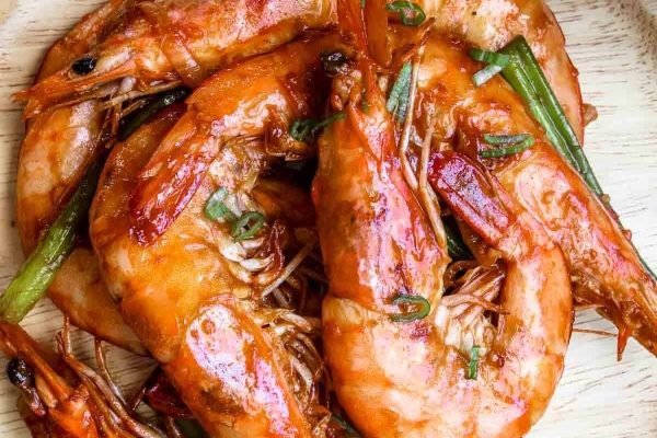 A plate of grilled shrimp on a wooden plate, perfect for seafood lovers.