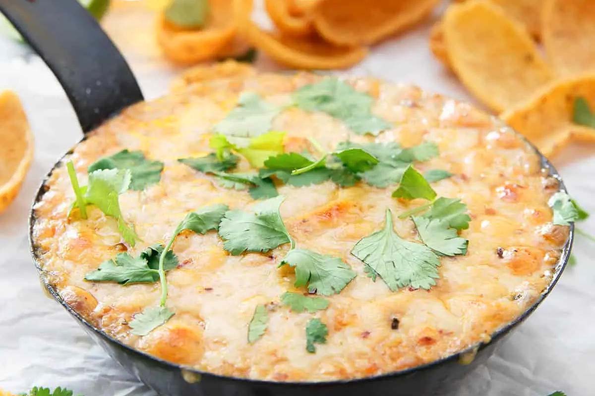 Game day cheesy corn dip in a skillet with tortilla chips.