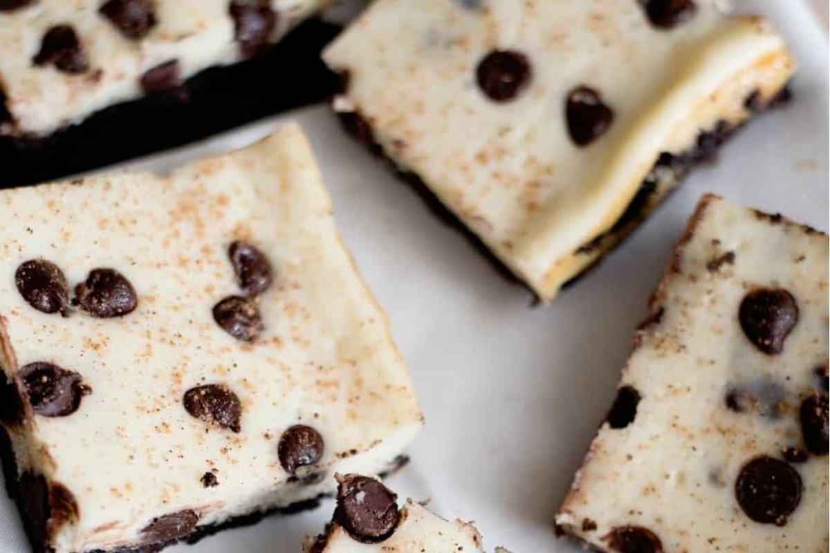 Chocolate chip cheesecake bars on a white plate, perfect for holiday eggnog recipes.