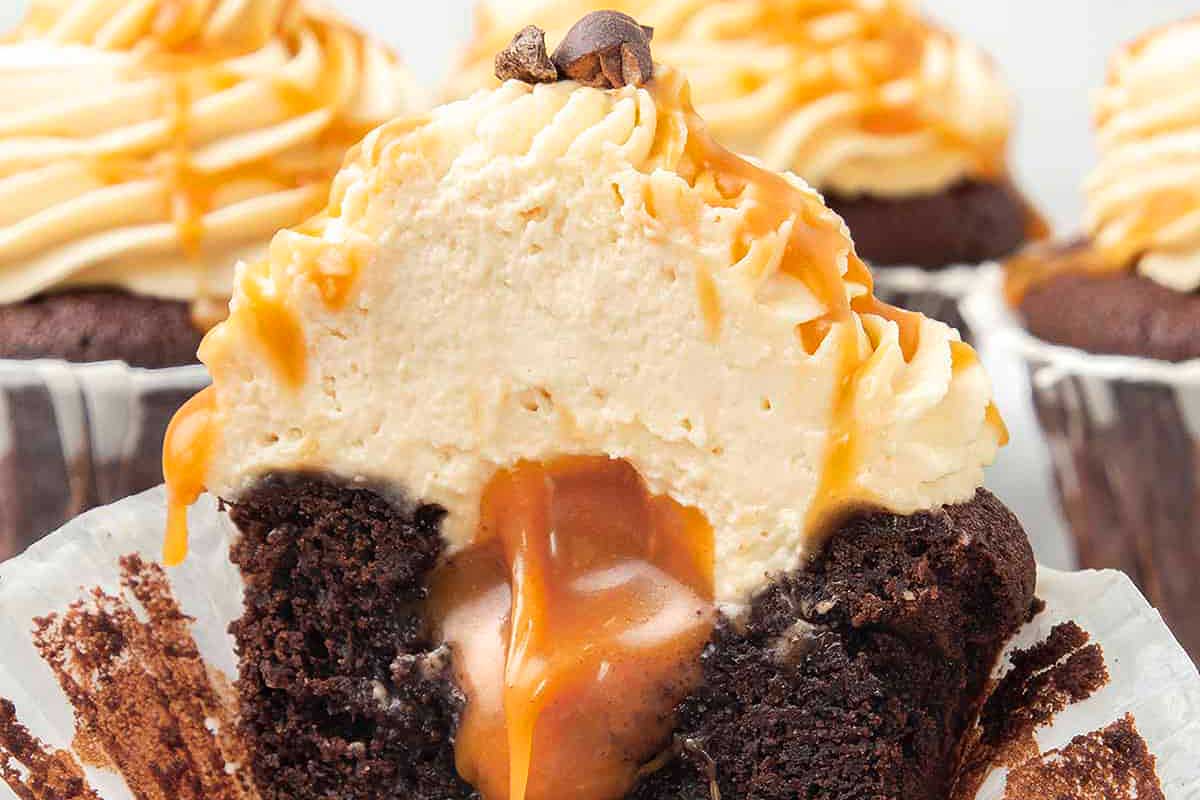 A chocolate cupcake with caramel sauce and a bite taken out of it.
