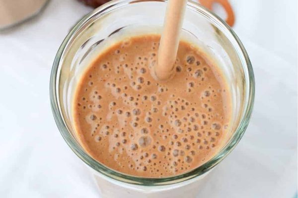 A glass of chocolate smoothie with a spoon in it, perfect for those craving a delicious milkshake.