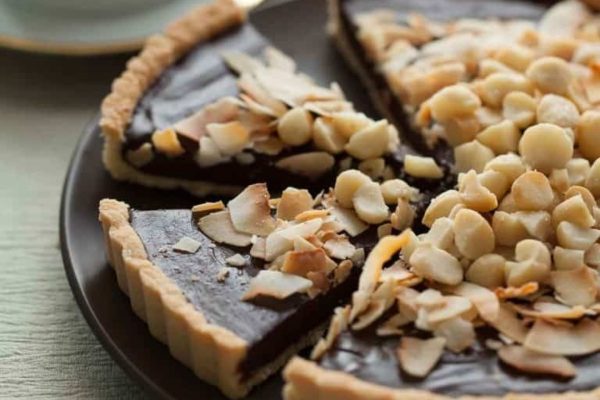 A chocolate tart with almonds on a plate.