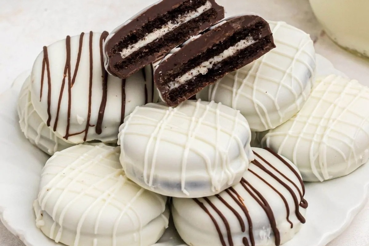 White chocolate Oreo cookies on a plate next to a glass of milk.