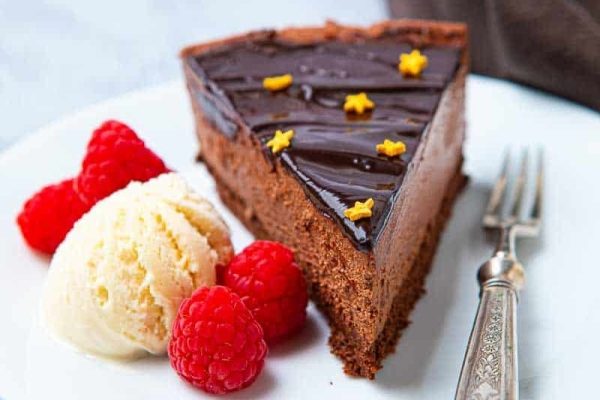 A festive slice of chocolate cake with raspberries and ice cream, perfect for Christmas desserts.