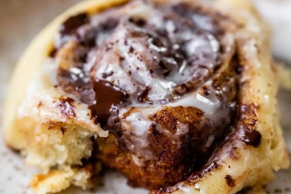 A close up of a cinnamon roll with chocolate icing on top.