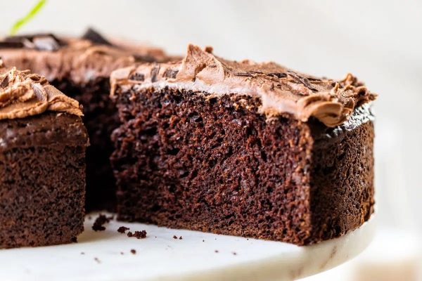 A slice of chocolate cake on a white plate that would be an indulgent addition to any Christmas desserts spread.