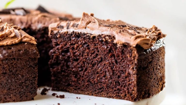 A slice of chocolate cake on a white plate that would be an indulgent addition to any Christmas desserts spread.